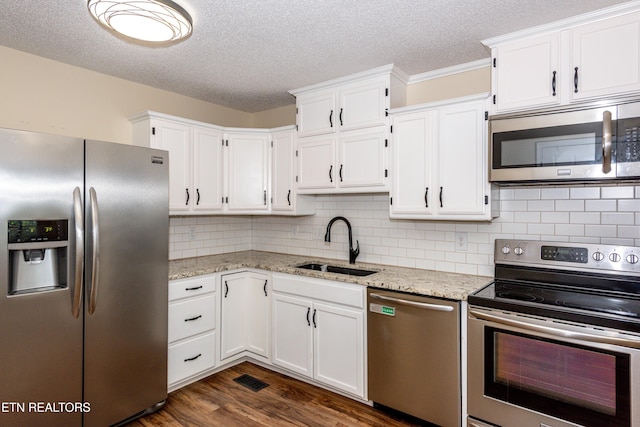 kitchen with a sink, appliances with stainless steel finishes, white cabinets, and dark wood-style floors