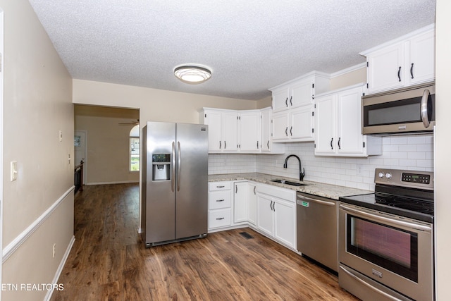 kitchen featuring tasteful backsplash, dark wood finished floors, a sink, white cabinets, and stainless steel appliances