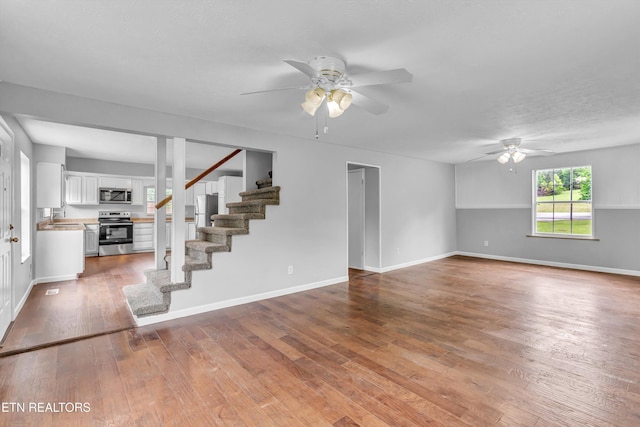 1921 Spring Hill Rd, Knoxville, TN 37914 - unfurnished living room with ceiling fan, stairs, wood finished floors, a sink, and baseboards