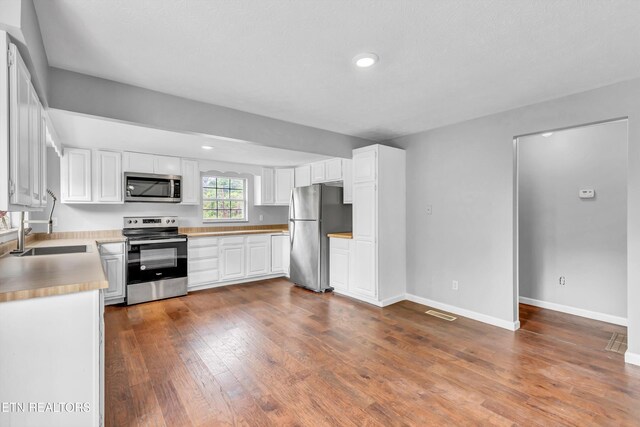 1921 Spring Hill Rd, Knoxville, TN 37914 - kitchen with stainless steel appliances, white cabinets, dark wood-type flooring, baseboards, and recessed lighting