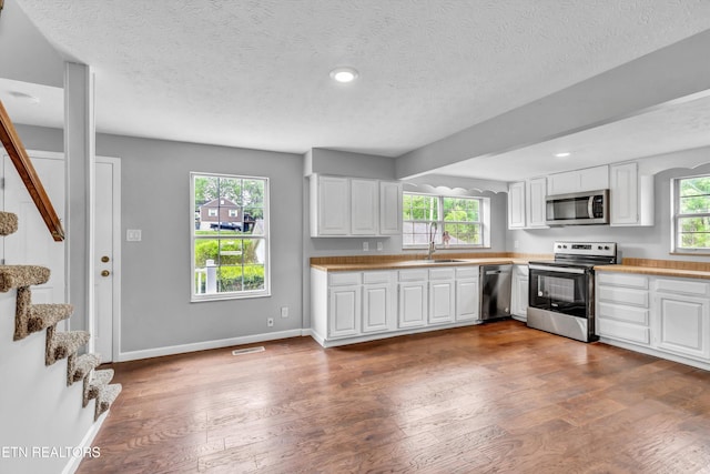 1921 Spring Hill Rd, Knoxville, TN 37914 - kitchen featuring appliances with stainless steel finishes, a sink, wood finished floors, white cabinetry, and a textured ceiling