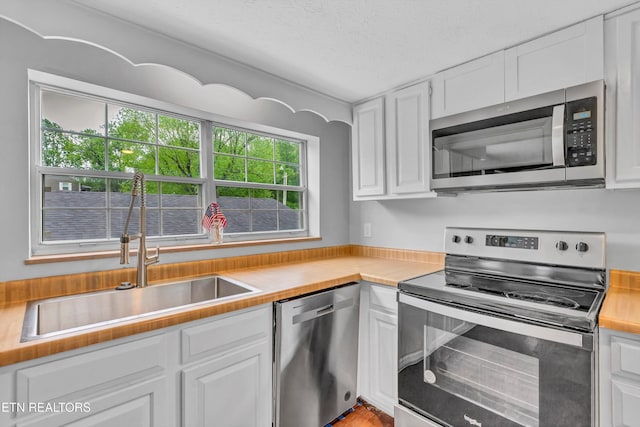 1921 Spring Hill Rd, Knoxville, TN 37914 - kitchen with appliances with stainless steel finishes, a sink, white cabinetry, and a textured ceiling