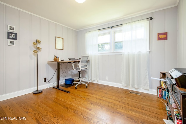 office area featuring a decorative wall, crown molding, wood finished floors, and visible vents