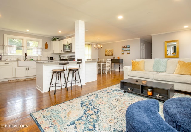living area with recessed lighting, wood finished floors, crown molding, and a notable chandelier
