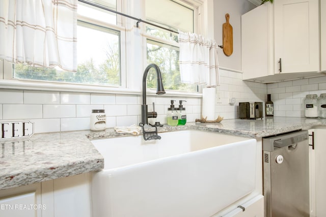 kitchen featuring backsplash, dishwasher, white cabinetry, and a sink