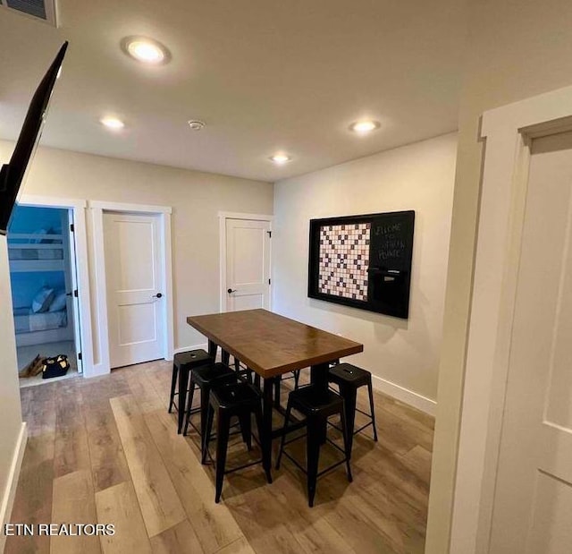 dining space with baseboards, wood finished floors, visible vents, and recessed lighting