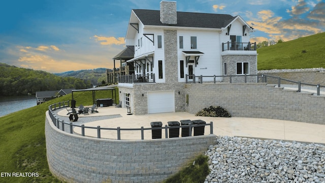 exterior space featuring a chimney, fence, a patio area, an attached garage, and a balcony