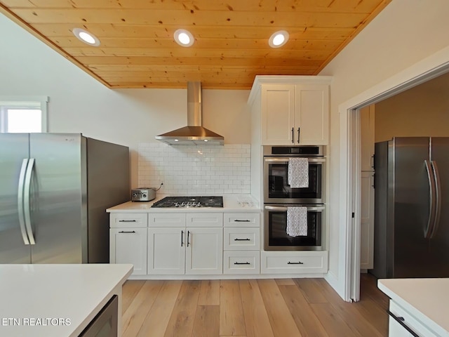 kitchen with wooden ceiling, wall chimney exhaust hood, appliances with stainless steel finishes, and light countertops