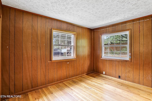 spare room featuring a textured ceiling, wood walls, and hardwood / wood-style flooring