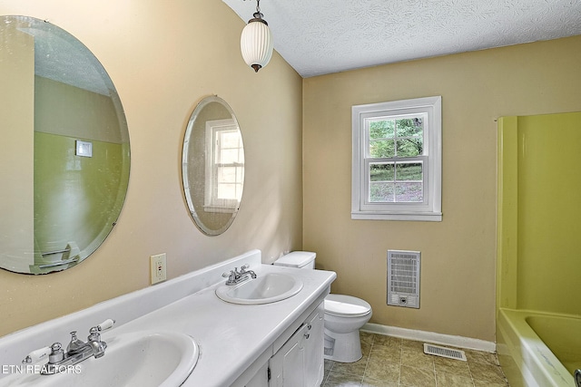 bathroom featuring toilet, heating unit, a sink, and visible vents