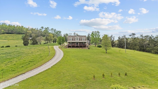 exterior space featuring a wooden deck, dirt driveway, and a front yard