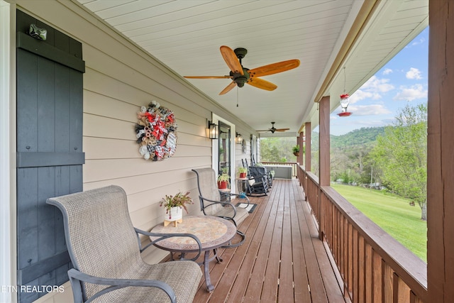 wooden deck with a yard, a ceiling fan, and covered porch
