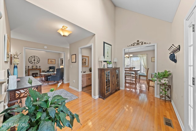 entryway with baseboards, a notable chandelier, visible vents, and light wood-style flooring