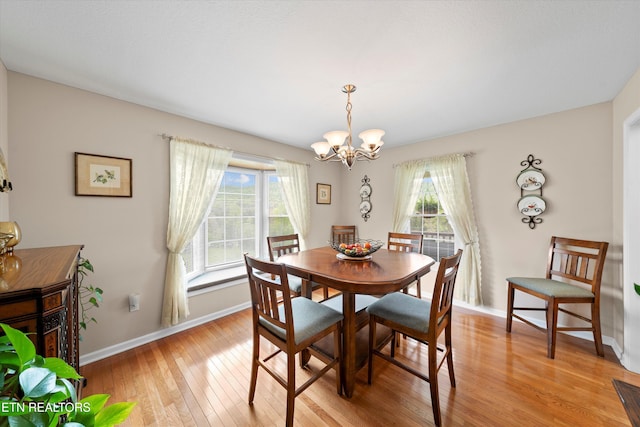 dining space with a wealth of natural light, baseboards, an inviting chandelier, and light wood-style flooring