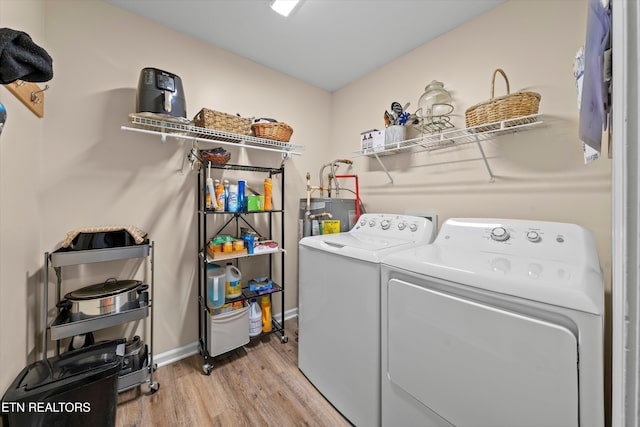 laundry area with washing machine and clothes dryer, water heater, light wood finished floors, baseboards, and laundry area