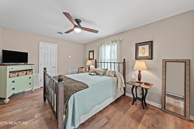 bedroom featuring visible vents, baseboards, a ceiling fan, and wood finished floors