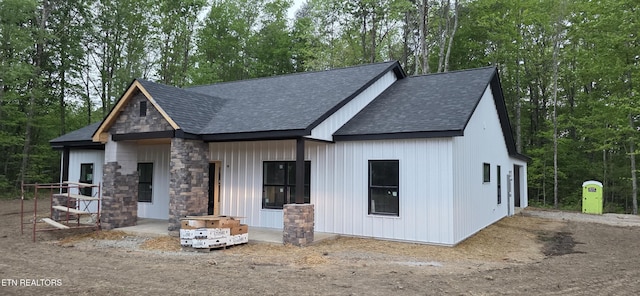 view of front of property with stone siding and roof with shingles