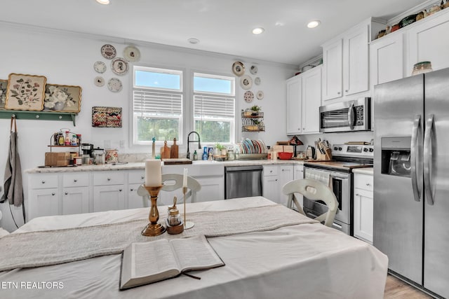 kitchen featuring ornamental molding, appliances with stainless steel finishes, and white cabinetry