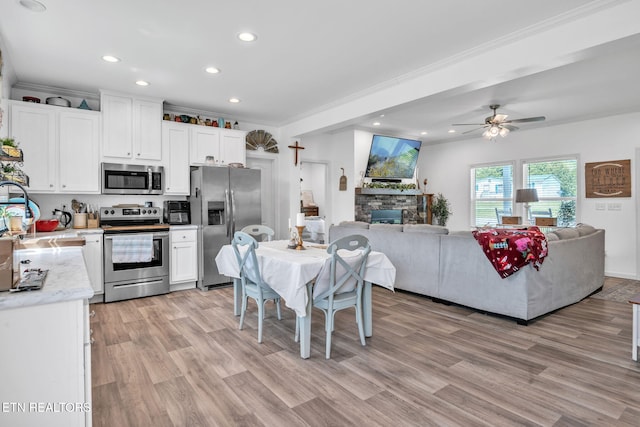 kitchen featuring open floor plan, stainless steel appliances, white cabinets, ornamental molding, and recessed lighting