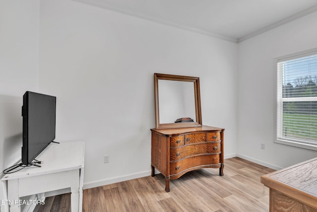 living area featuring baseboards, ornamental molding, and light wood-type flooring