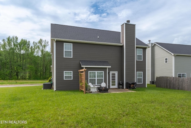 back of house featuring a lawn, a chimney, cooling unit, and a patio