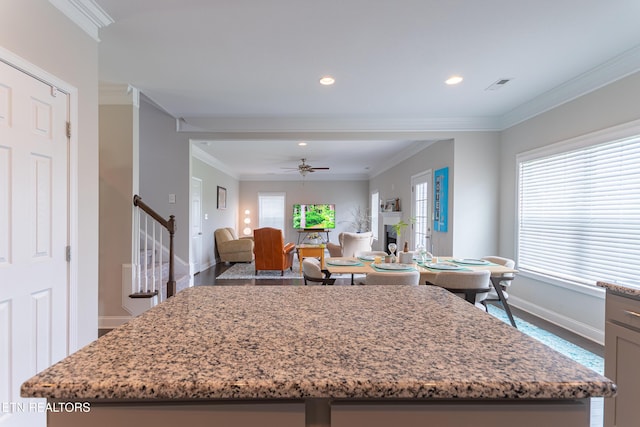 kitchen featuring light stone counters, visible vents, a kitchen island, and baseboards