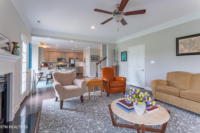 living room with a fireplace, a ceiling fan, ornamental molding, and baseboards