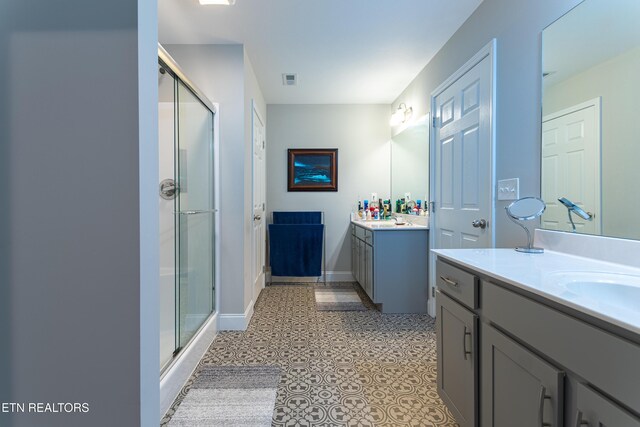full bathroom with baseboards, visible vents, a stall shower, and two vanities