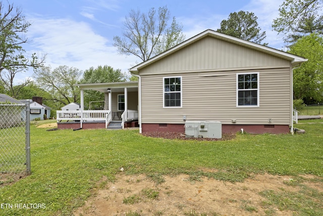 back of house featuring a yard, crawl space, a porch, and fence