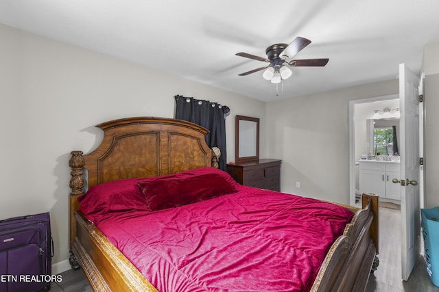 bedroom featuring wood finished floors, a ceiling fan, ensuite bath, and baseboards