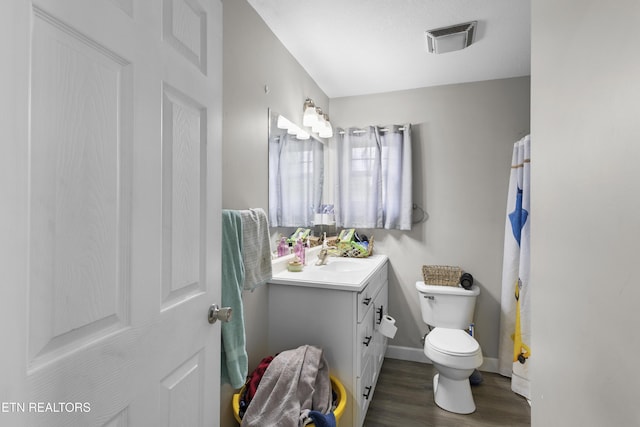 bathroom featuring visible vents, baseboards, toilet, wood finished floors, and vanity