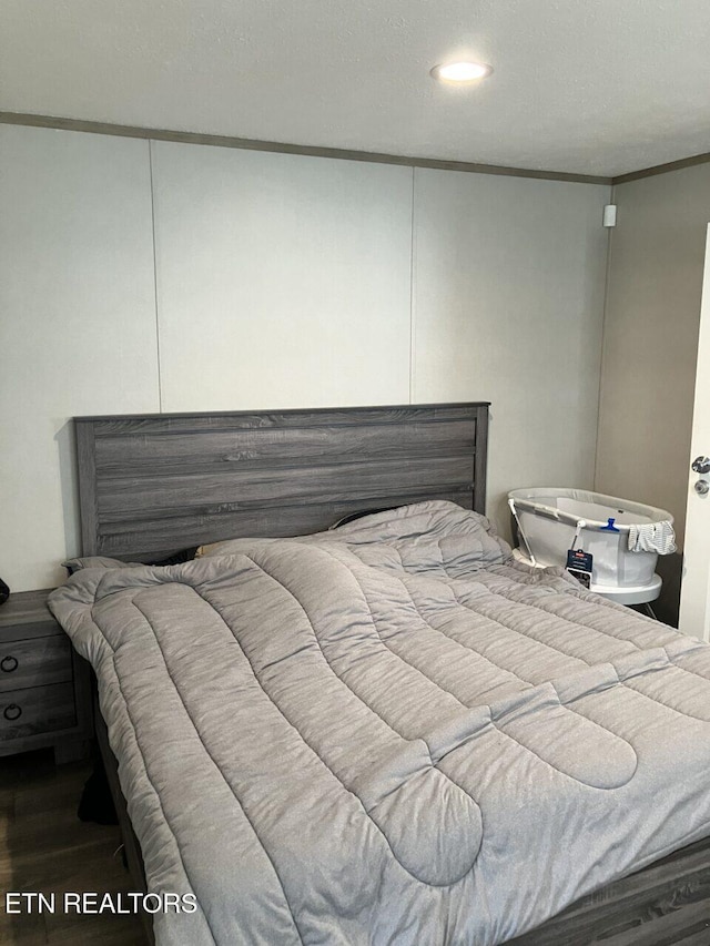 bedroom with wood finished floors and crown molding