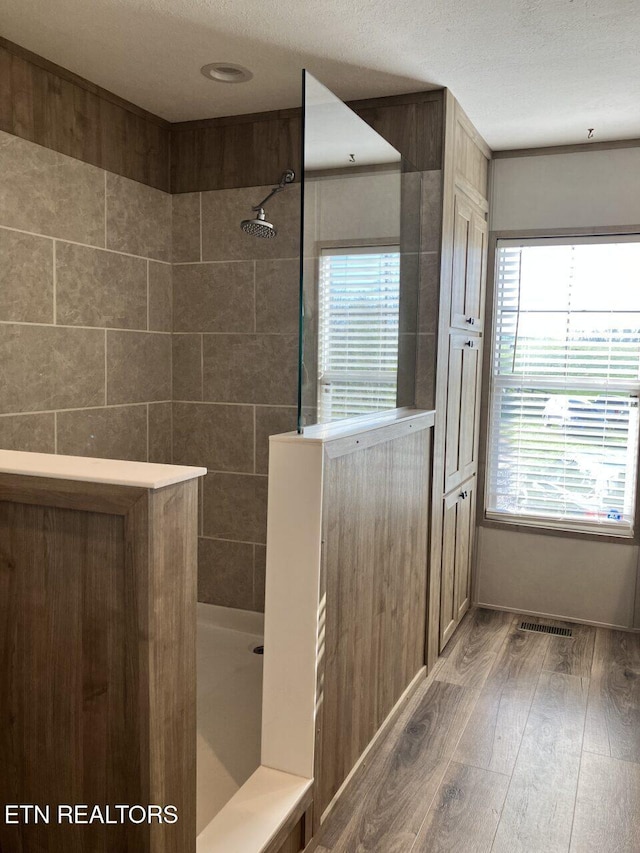 bathroom featuring visible vents, walk in shower, a healthy amount of sunlight, and wood-type flooring