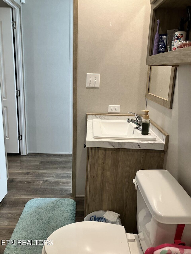 half bath with wood finished floors, toilet, and a sink