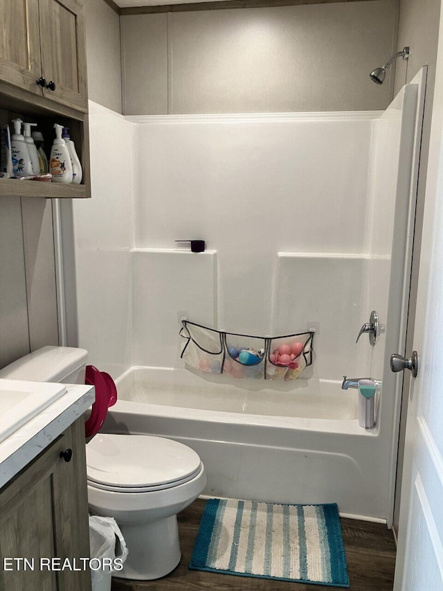 bathroom featuring wood finished floors, toilet, vanity, and bathtub / shower combination