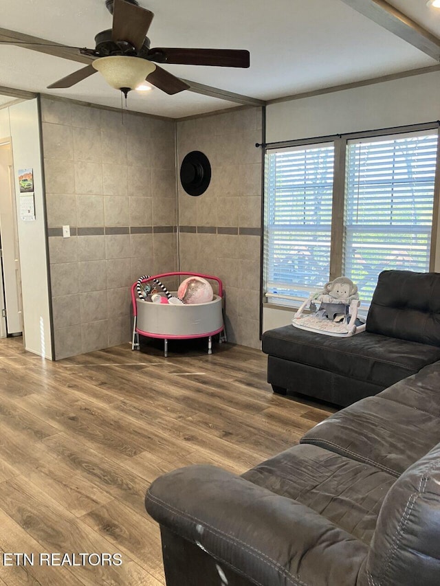 living room featuring tile walls, a ceiling fan, and wood finished floors