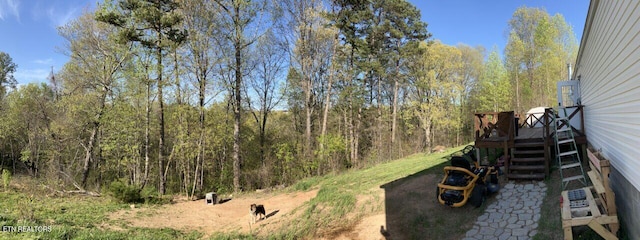 view of yard featuring a wooden deck and a view of trees