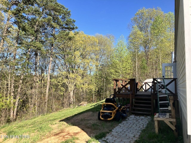 view of yard featuring a forest view, a wooden deck, and stairway