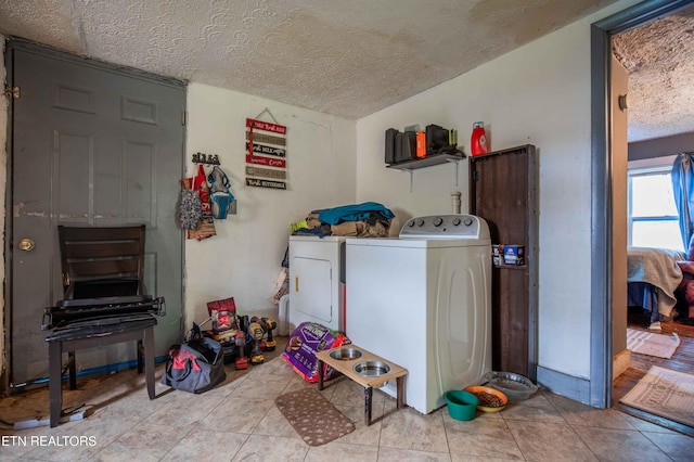 washroom with a textured ceiling, washing machine and clothes dryer, tile patterned floors, and laundry area