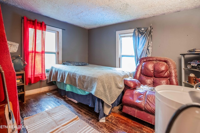 bedroom featuring wood-type flooring, baseboards, and a textured ceiling