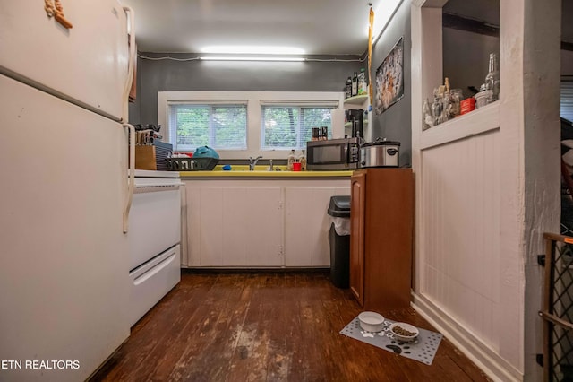 kitchen featuring stainless steel microwave, white cabinetry, stove, dark wood-style floors, and freestanding refrigerator