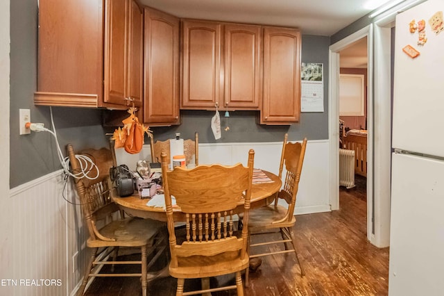 dining area featuring radiator, dark wood-style floors, and wainscoting