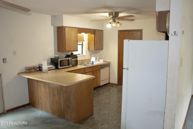 kitchen featuring a sink, ceiling fan, light countertops, white appliances, and a peninsula