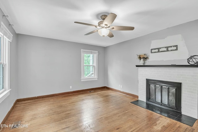 unfurnished living room with baseboards, a ceiling fan, wood finished floors, and a fireplace