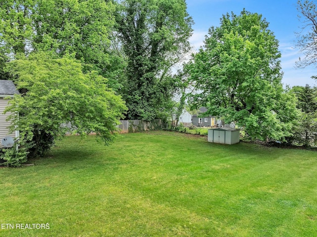 view of yard featuring fence, an outbuilding, and a shed