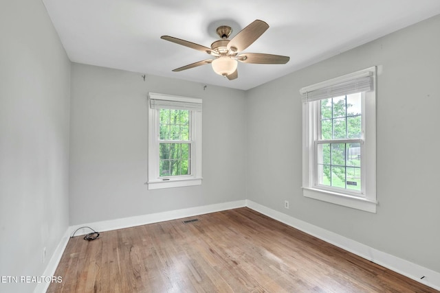 spare room with baseboards, wood finished floors, visible vents, and a ceiling fan