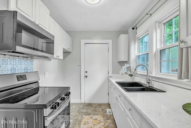 kitchen featuring white cabinets, baseboards, a sink, and appliances with stainless steel finishes