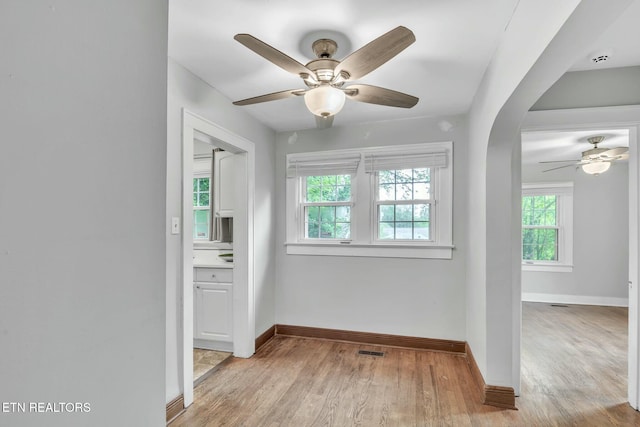interior space with light wood finished floors, plenty of natural light, a ceiling fan, and baseboards