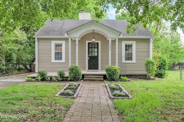 bungalow-style home with a chimney, a front lawn, roof with shingles, and fence