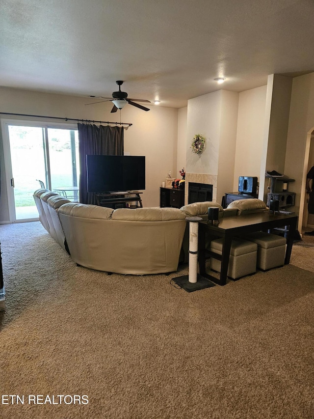 carpeted living area with a tile fireplace and ceiling fan